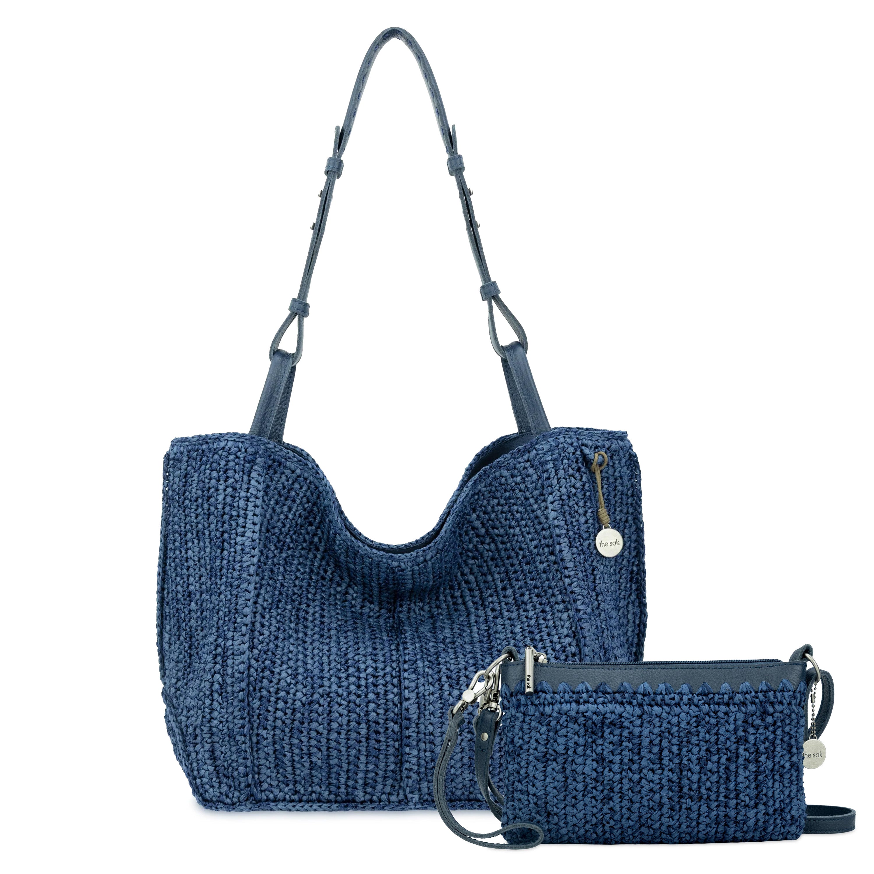 Navy blue quilted tote bag with shoulder straps and matching smaller wristlet clutch with wrist strap.